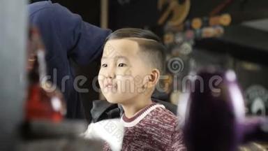 戴着黑色手套的理发师给一个亚洲孩子做一个<strong>发型</strong>，用刷子60fps从脖子上去除<strong>剪</strong>掉的头发